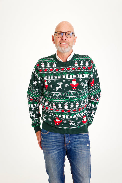 En mand poserer i en grøn julesweater med nisser, rensdyr og mønster på.
