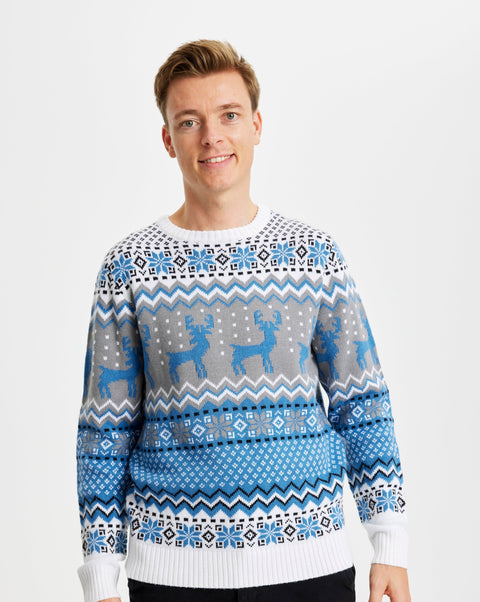 En smilende mand iført en blå julesweater med rensdyr på.