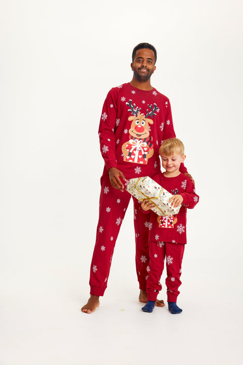 Et barn med en julegave og en mand iført røde julepyjamas.