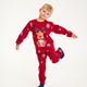 Et poserende barn iført røde julepyjamas med snefnug på.