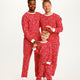 To mænd og et barn poserer i en rød julepyjamas med forskelligeartet mønster på.