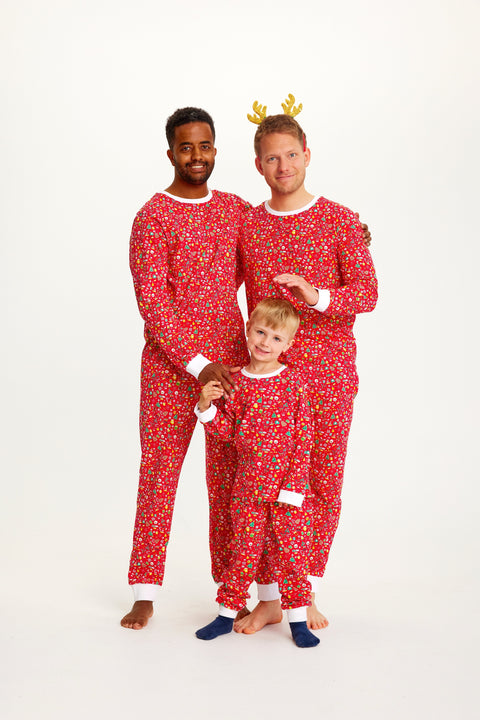 To mænd og et barn poserer i en rød julepyjamas med forskelligeartet mønster på.