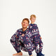 En mand og et barn poserer med blå julepyjamas på.